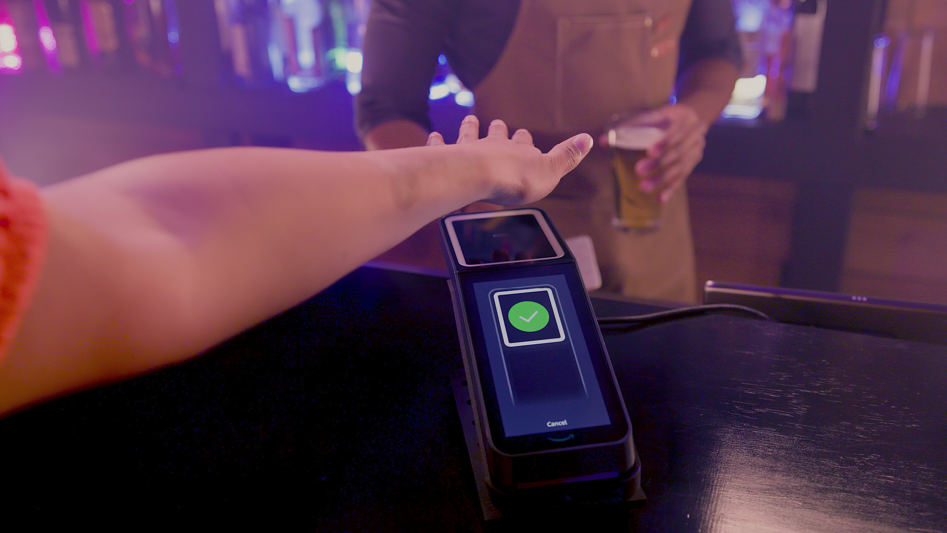 A photo of a customer paying for a beer at a bar using Amazon One.