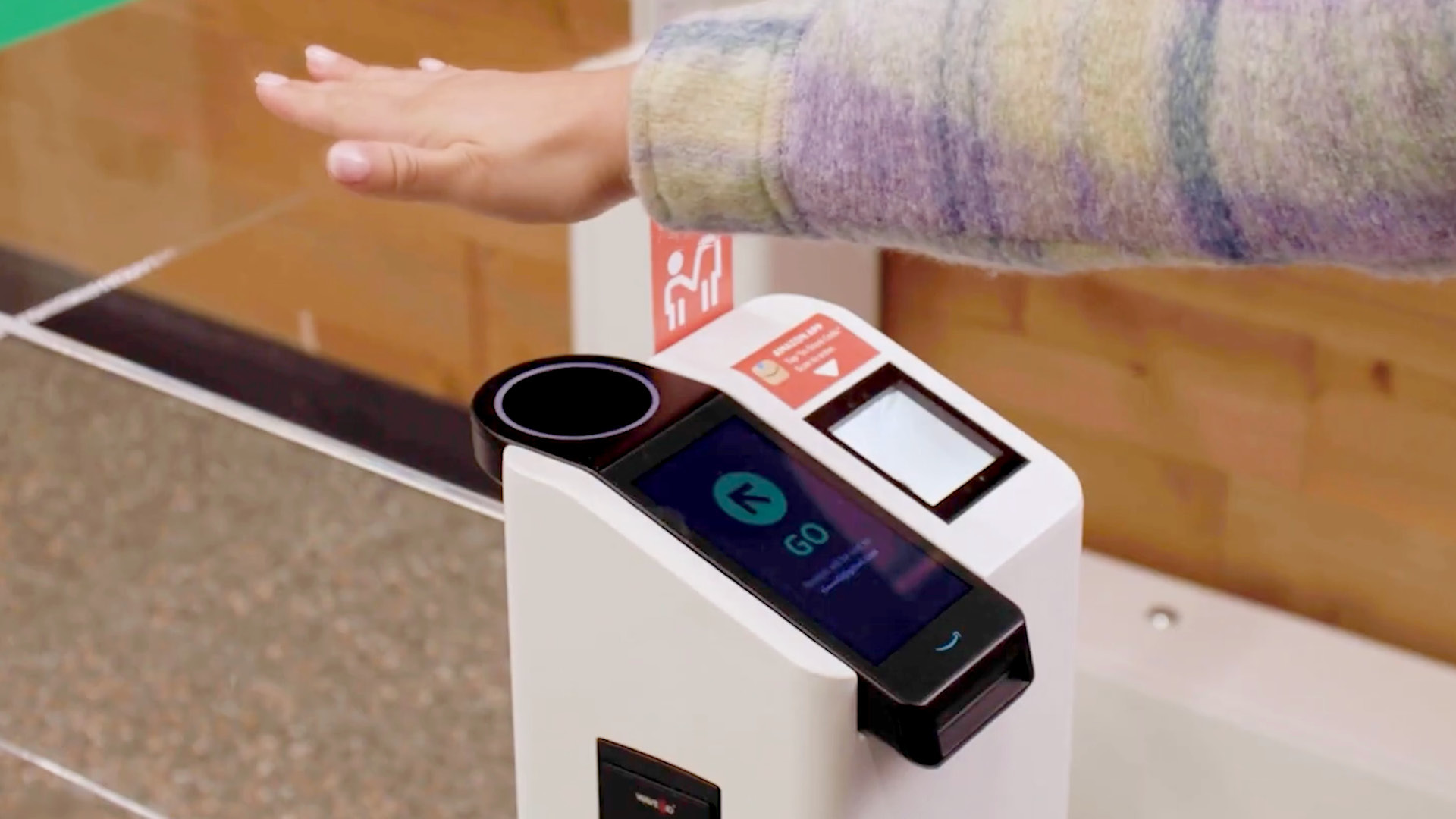 A photo of a hand hovering an Amazon One scanner.