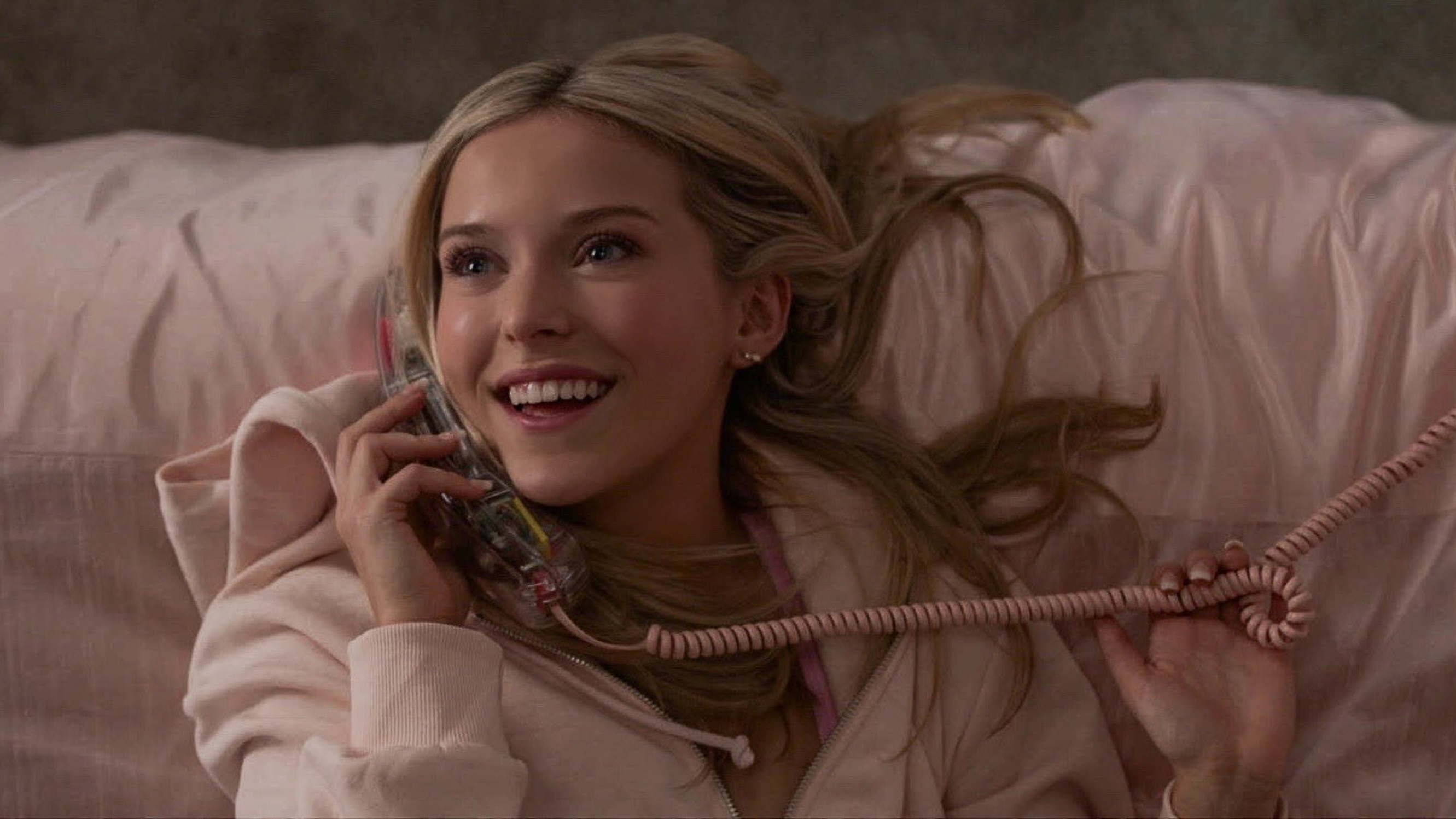 Elle Woods laughing on the phone in pink bedding in the Amazon Prime series Elle