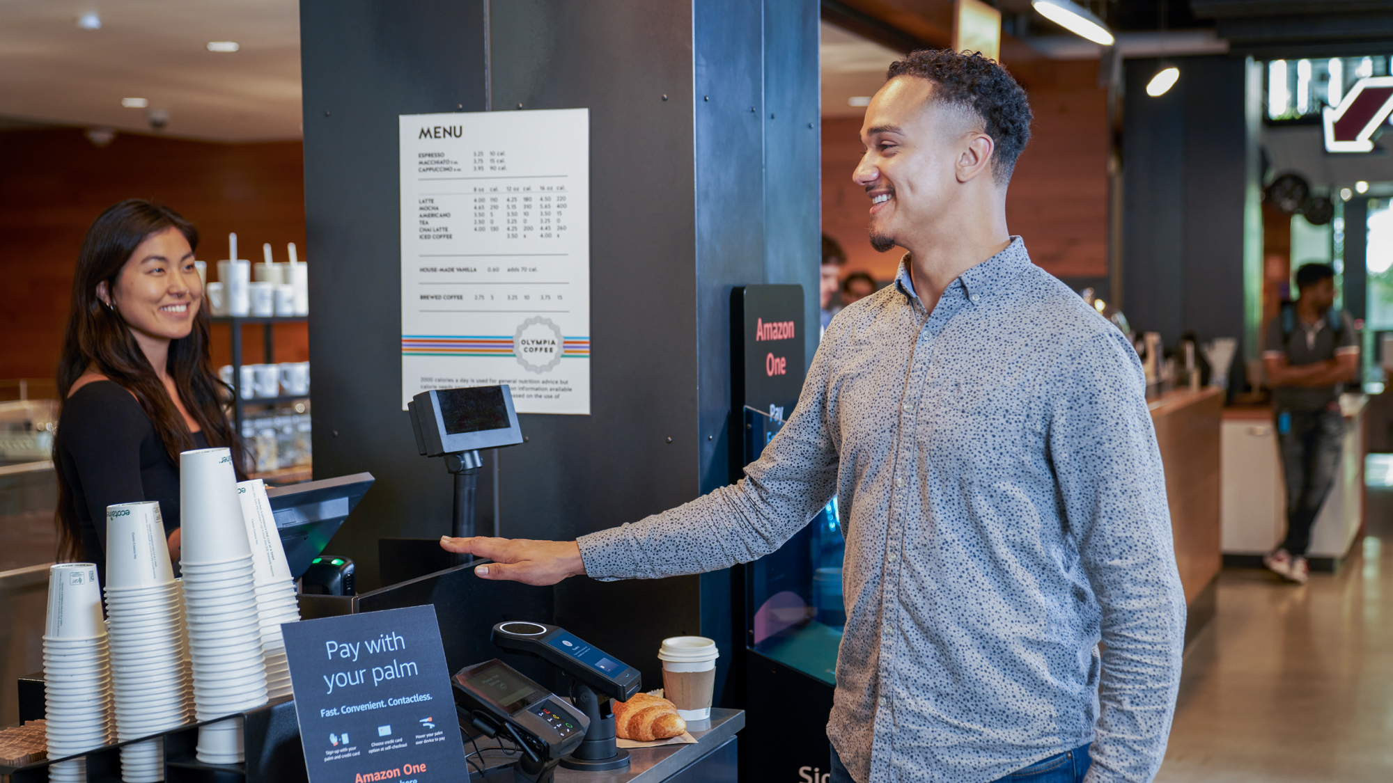 A photo of a customer purchasing a coffee and croissant with Amazon One.