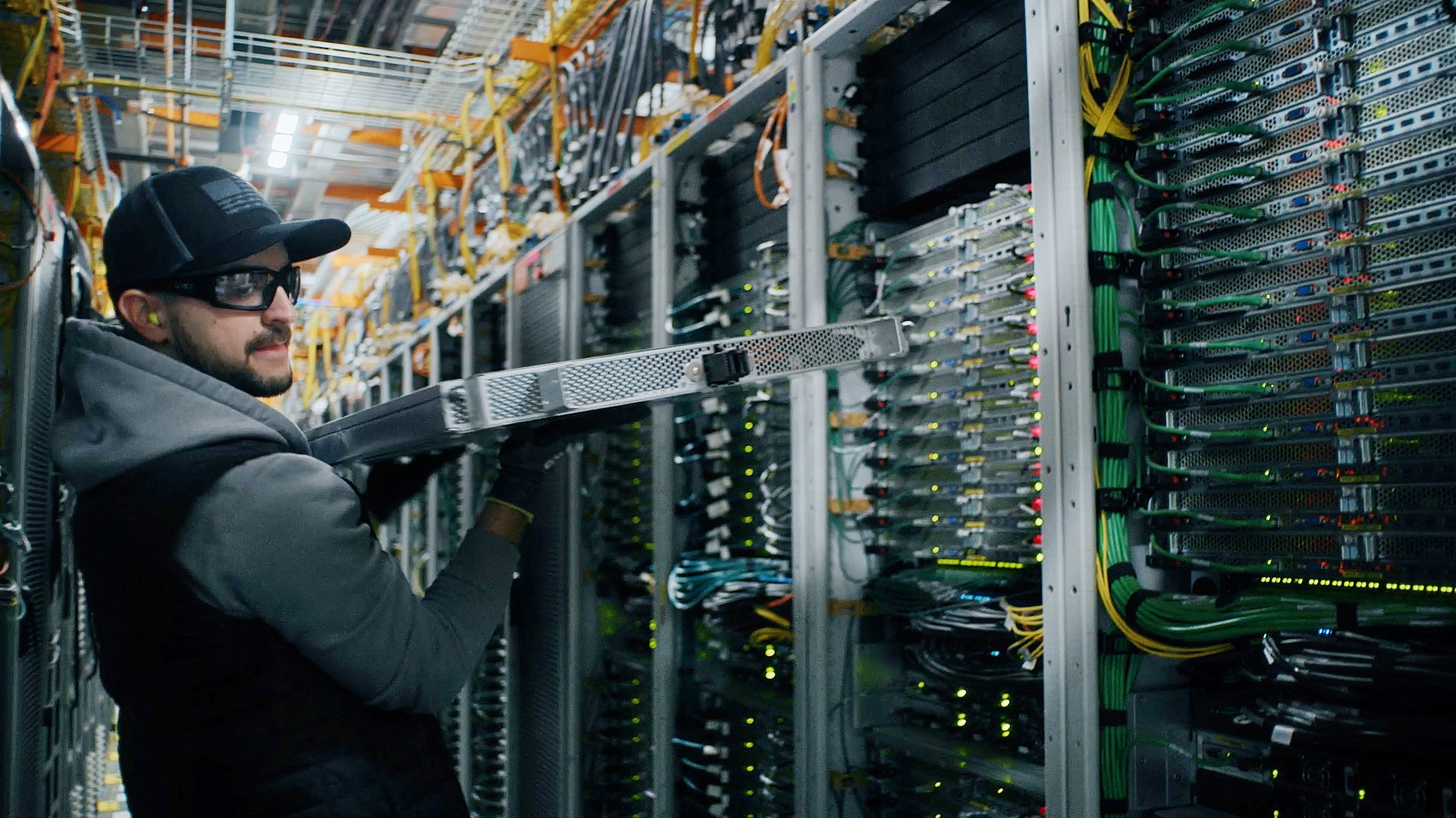 A photo of Fidel Contreras holding a server rack within an AWS data center.