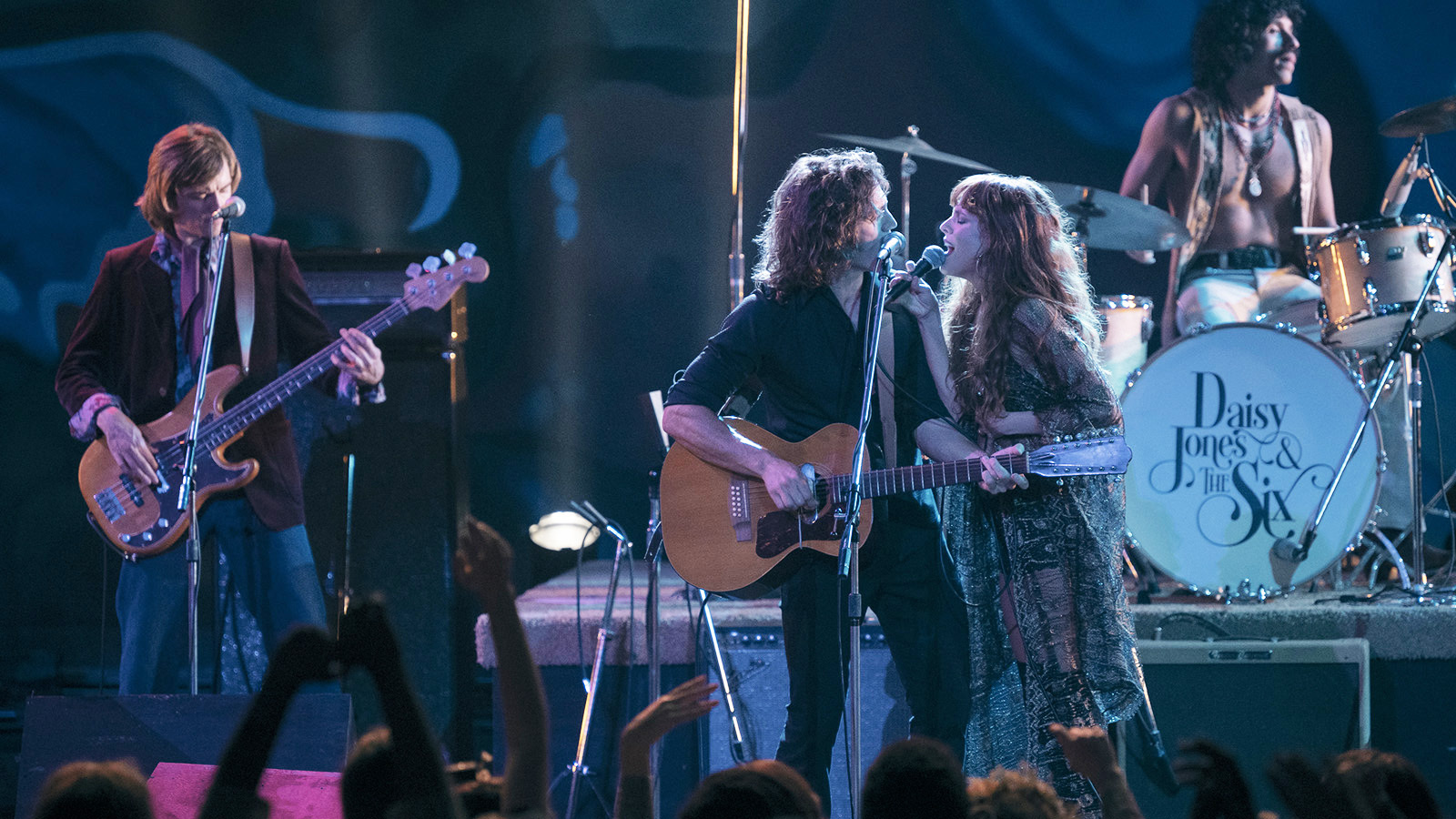 A still of Riley Keough as Daisy Jones and Sam Chaflin as Billy Dunne singing on stage in Prime Video's limited series, Daisy Jones & The Six.'