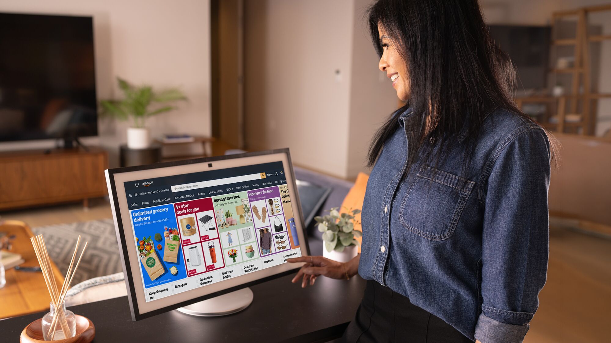 Person browsing Amazon storefront on a large desktop touchscreen while standing at home