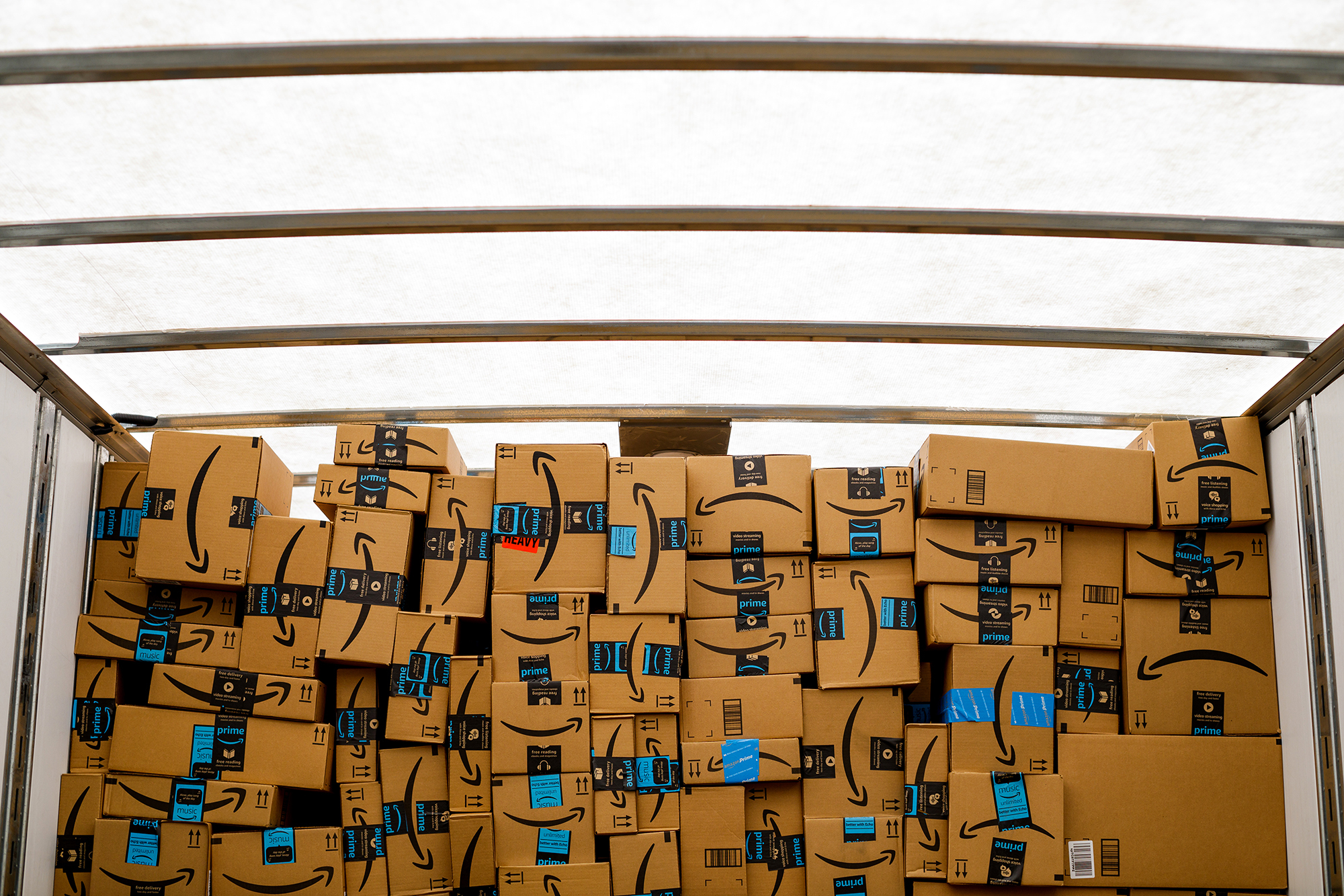 Amazon boxes stacked in a well-lit space inside a truck.