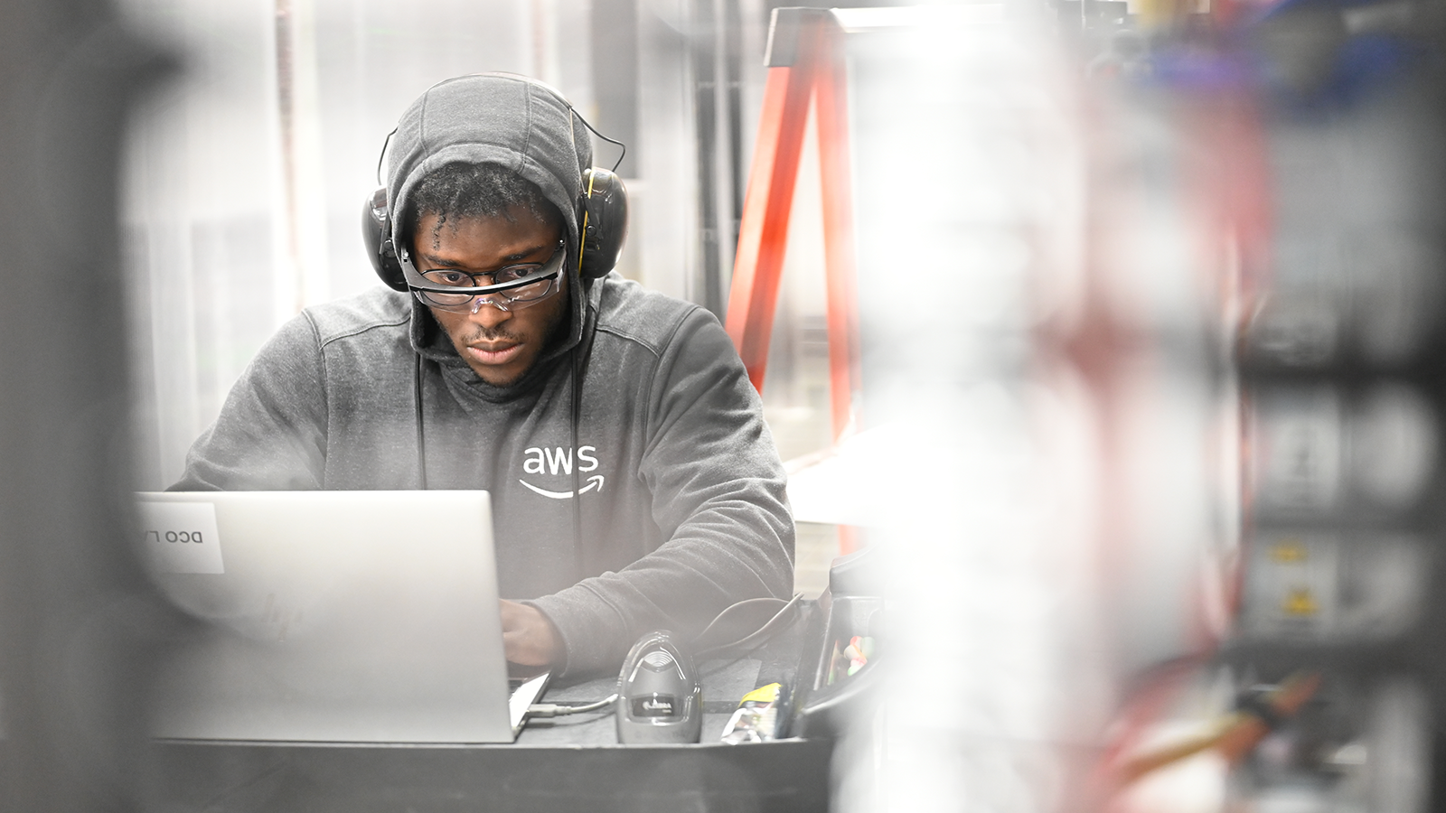 A photo of a data center technician working at a desk inside a data center on a laptop device.