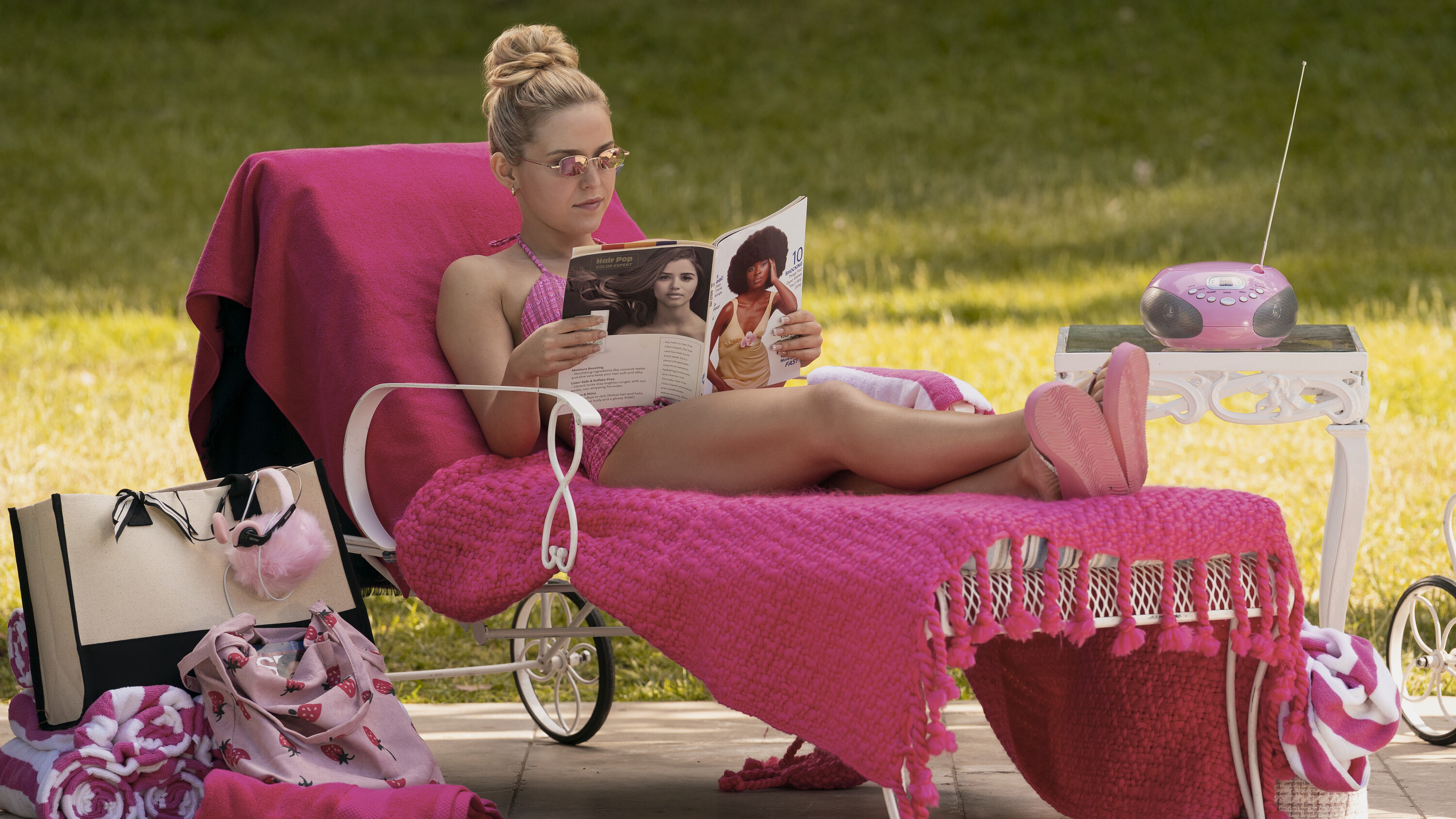 Elle Woods on a pink pool lounge chair reading a magazine in the Amazon Prime series Elle